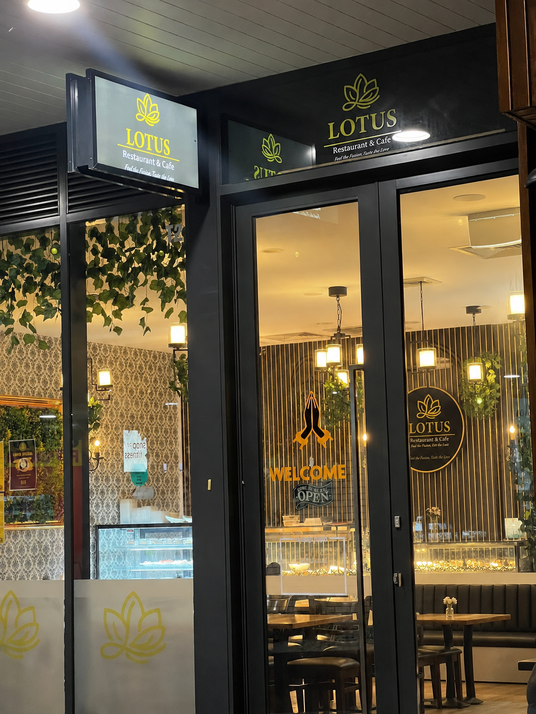 Lotus cafe entrance at night with glowing gold signage and warm interior lights