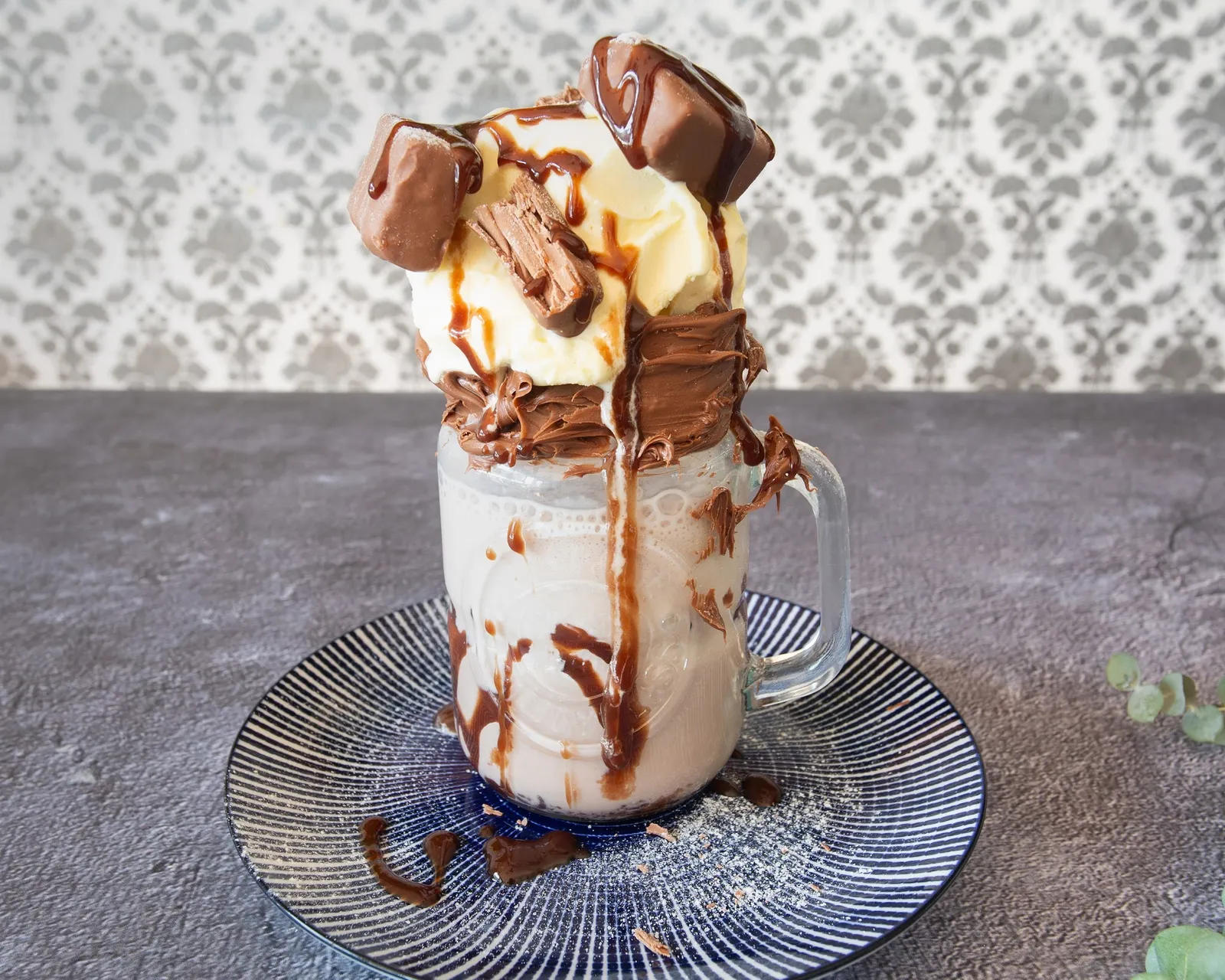 Chocolate milkshake in a mason jar topped with cream and chocolate drizzle
