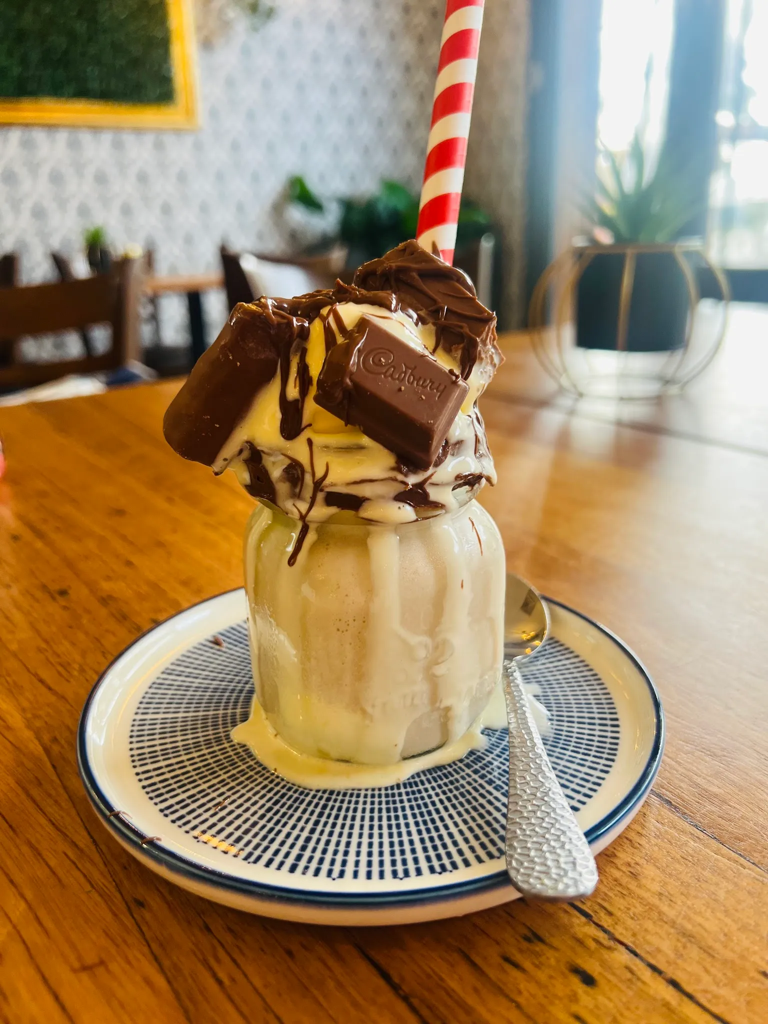 Milkshake mason jar topped with cream and chocolate on a cafe table